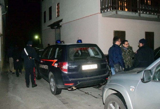 Carabinieri in divisa ed in borghese davanti l'ingresso dell'abitazione
