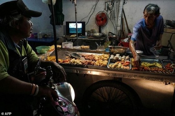 A street food vendor talks to a customer in the Phrakanong district of Bangkok