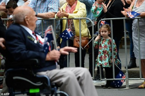 A young girl looks at a war veteran taking part in the Anzac Day parade in Sydney on April 25, 2017