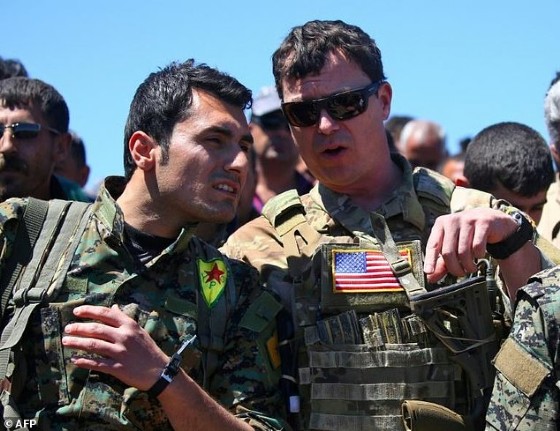 A US officer speaks with a fighter from the Kurdish People's Protection Units (YPG) at the site of Turkish air strikes in northeastern Syria on April 25, 2017