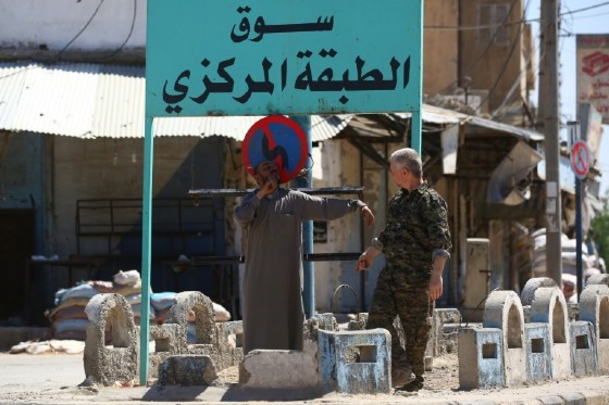 A man speaks to a member of the Syrian Democratic Forces (SDF) in the town of Tabqa on May 12, 2017