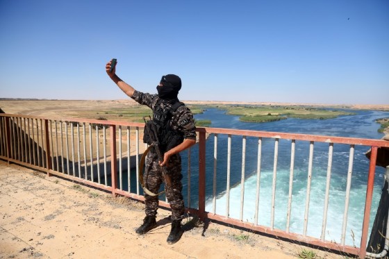 A member of the Special forces from the US-backed Syrian Democratic Forces (SDF) takes a picture at the Tabqa dam, on May 12, 2017, after it was recaptured from Islamic State group fighters