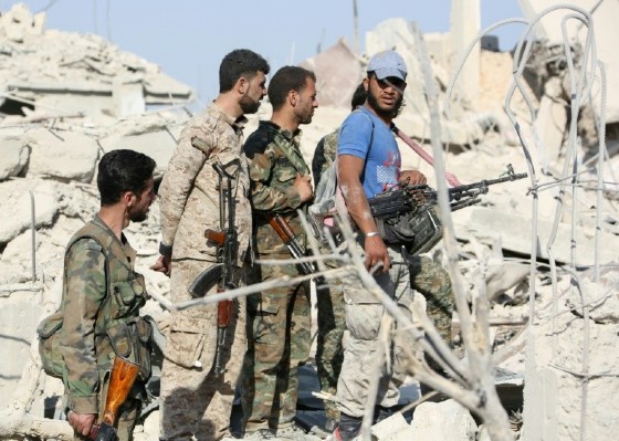 Syrian pro-government forces amid the rubble of destroyed buildings as they advance through Qabun on the outskirts of Damascus on May 13, 2017