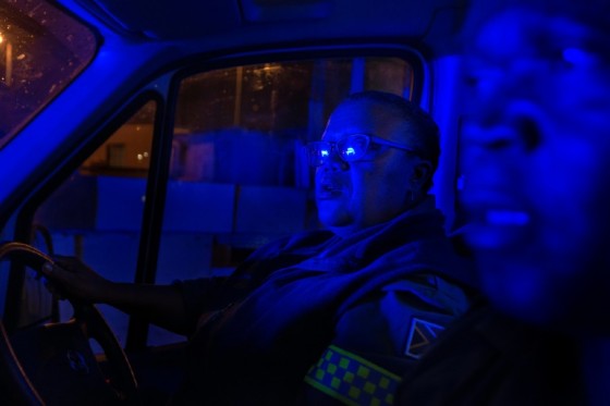 Paramedics Patricia September and Simphiwe Ngavu are bathed in the blue light of the South African Police Services van sticking close to them as they attend to a call in the crime-ridden Cape Town township of Nyanga