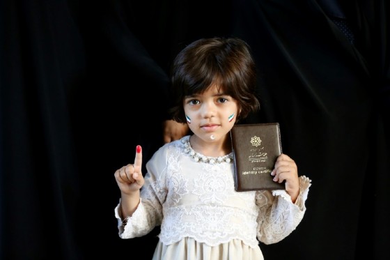 An Iranian girl shows her ink-stained finger and the ID of her mother who voted in presidential elections at a polling station in southern Tehran on May 19, 2017