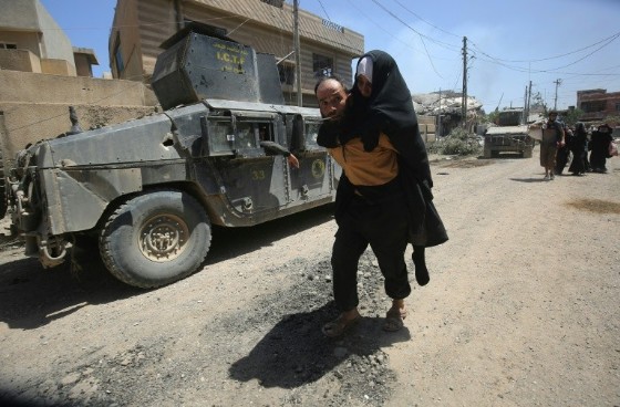 Man carries an elderly woman displaced from western Mosul as Iraqi security forces advance against Islamic State (IS) group fighters