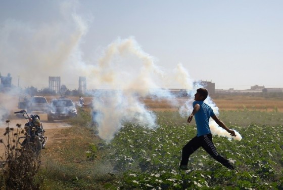 A Palestinian protester hurls a teargas canister back at Israeli soldiers during clashes near the border fence east of Gaza City on May 19, 2017