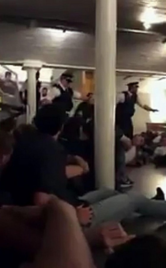 Un fermo immagine in cui si vede la polizia fare irruzione in un bar dove regnano caos e concitazione