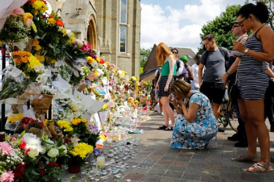 People look at floral tributes for victims of the Grenfell Tower block fire that have been left outside the Notting Hill Methodist Church in west London, on June 17, 2017