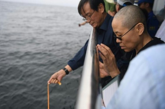 This handout photo provided by the Shenyang Municipal Information Office shows late Nobel laureate Liu Xiaobo's wife Liu Xia praying as they bury Liu's ashes at sea off the coast of Dalian