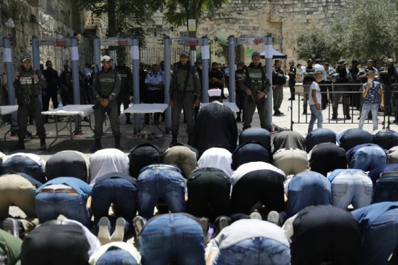 Israeli border policemen stand watch as Muslim worshippers pray outside an entrance to the Al-Aqsa mosque compound on July 16, 2017 in protest at new security measures including metal detectors and cameras