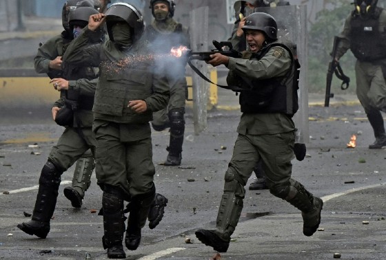 A member of the national guard fires his shotgun at opposition demonstrators during clashes in Caracas on July 28, 2017
