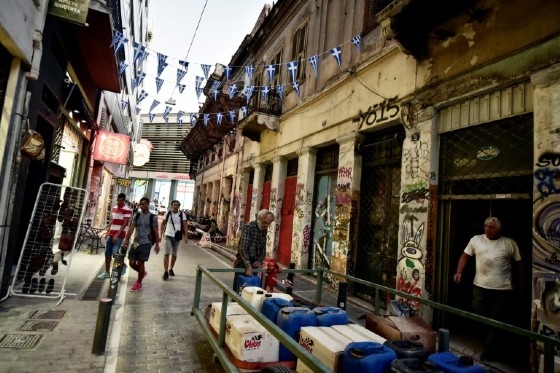People unload goods by an abandoned neoclassical building in the Monastiraki area of Athens