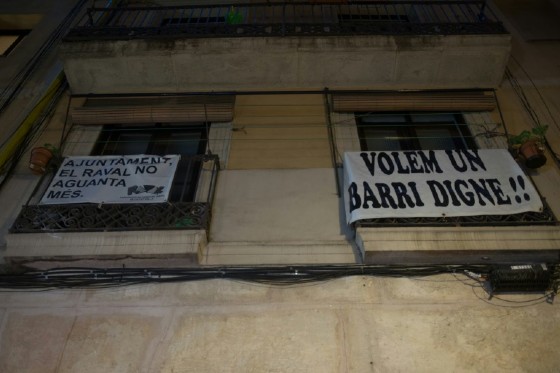 A banner reading "We want a dignified neighbourhood" hung from a balcony to protest drug flats in Raval, Barcelona