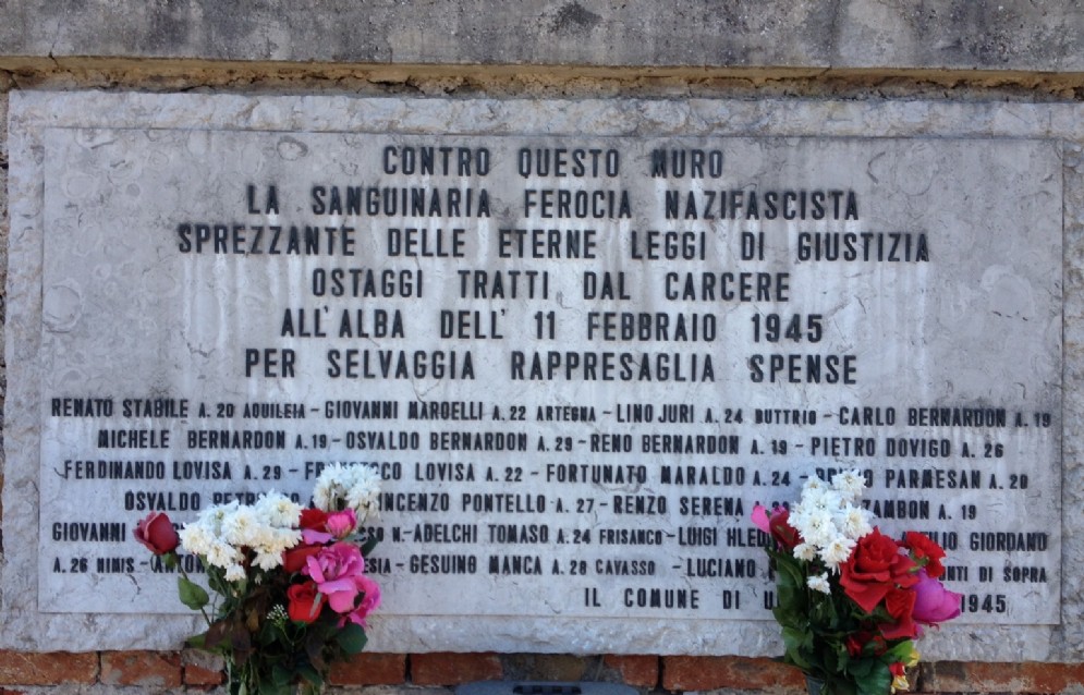 La lapide a ricordo dei 23 partigiani fucilati davanti al cimitero