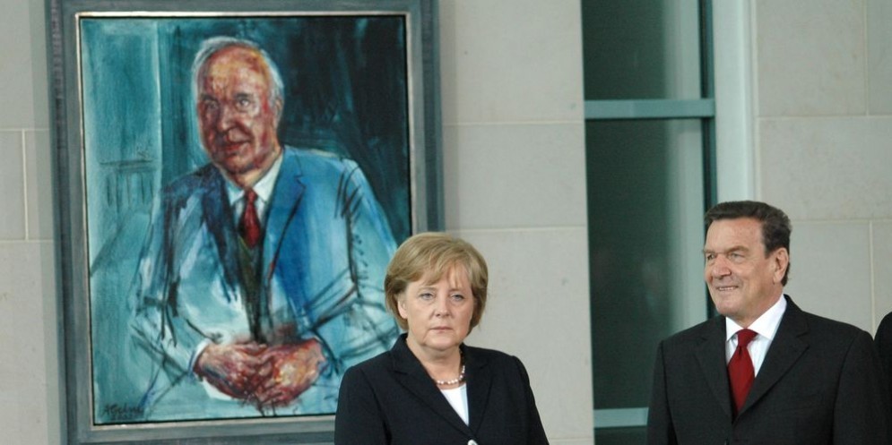 Angela Merkel con il suo predecessore Gerard Shroeder, davanti a un ritratto di Helmut Kohl.