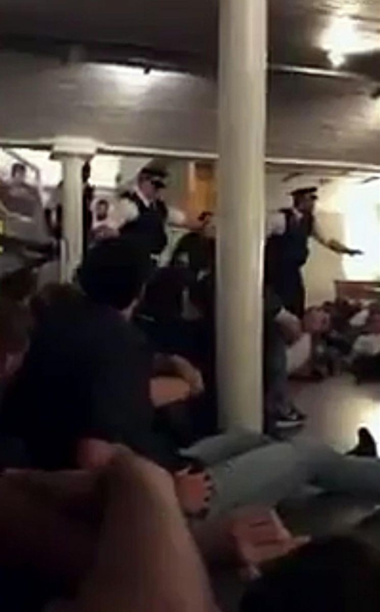 Un fermo immagine in cui si vede la polizia fare irruzione in un bar dove regnano caos e concitazione