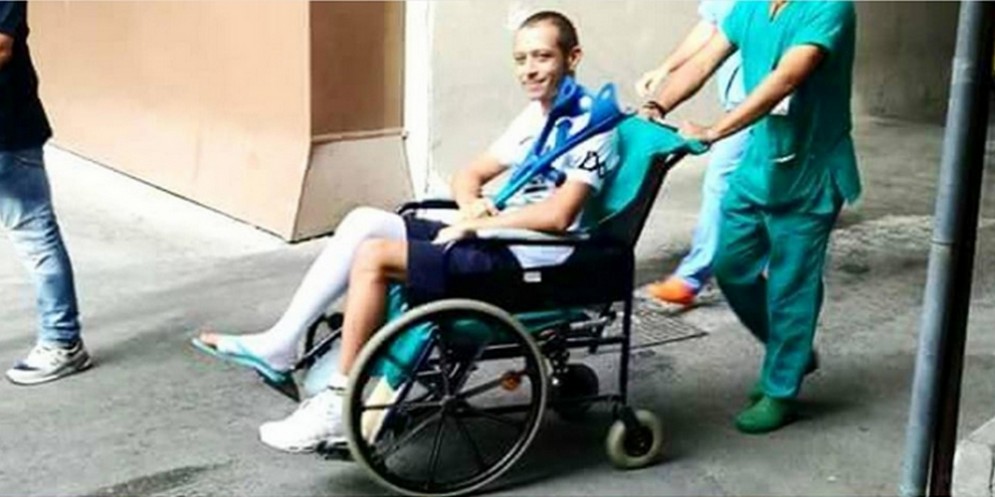 Valentino Rossi in uscita dall'ospedale di Ancona in sedia a rotelle e con il gesso alla gamba