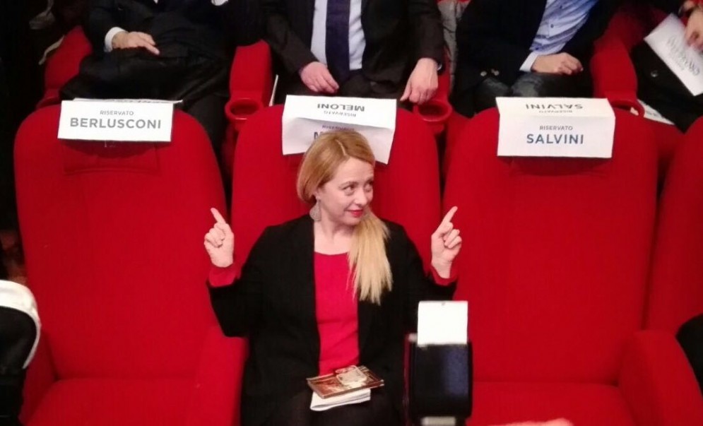 Giorgia Meloni in mezzo alle sedie lasciate vuote da Silvio Berlusconi e Matteo Salvini