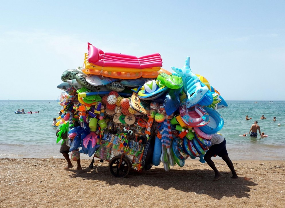 Un ambulante cammina sulla spiaggia di Santa Severa, 14 luglio 2018