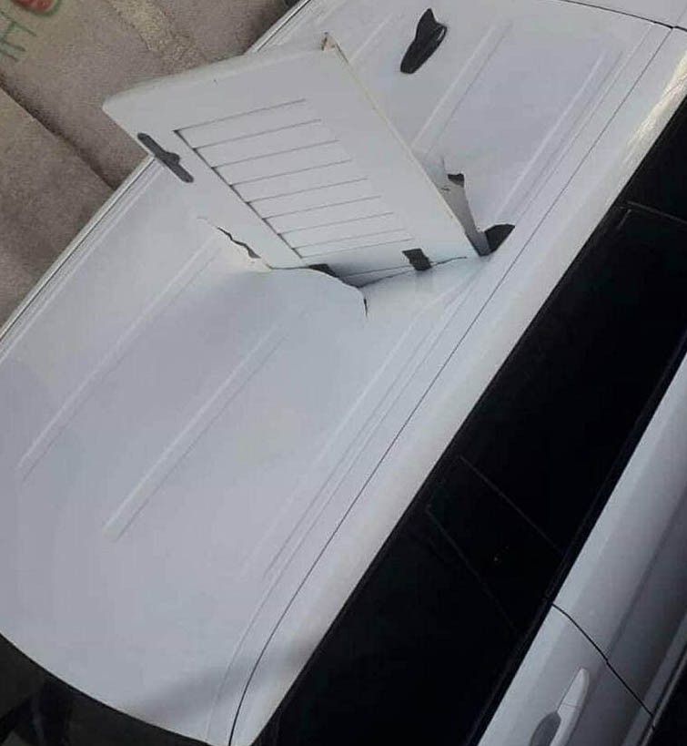 Scuretto di una finestra sfonda il tettuccio di un'auto in sosta