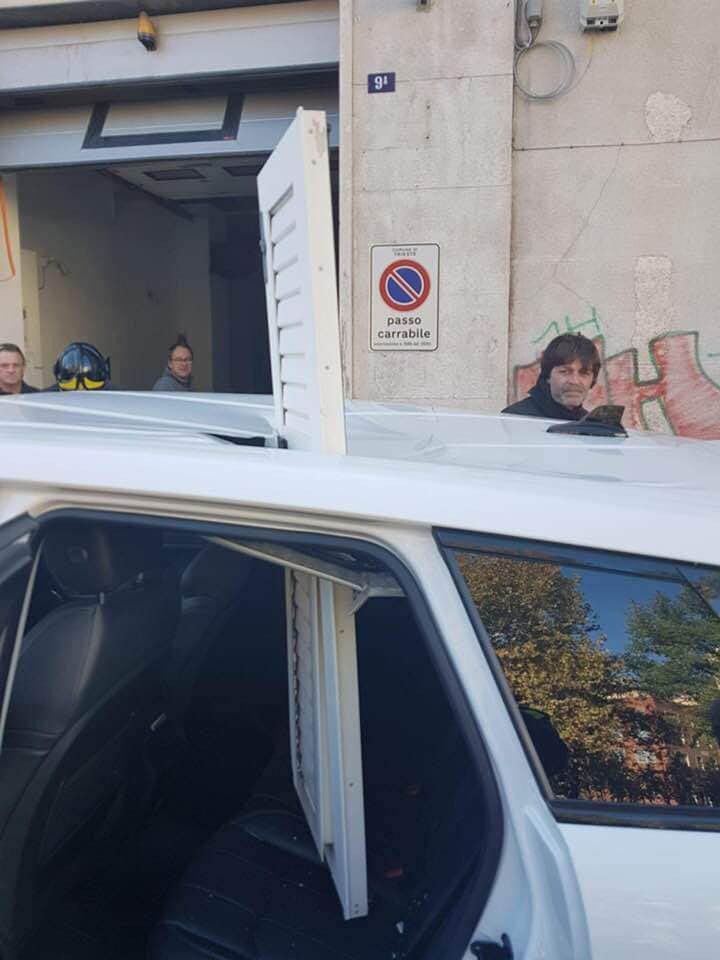 Scuretto di una finestra sfonda il tettuccio di un'auto in sosta