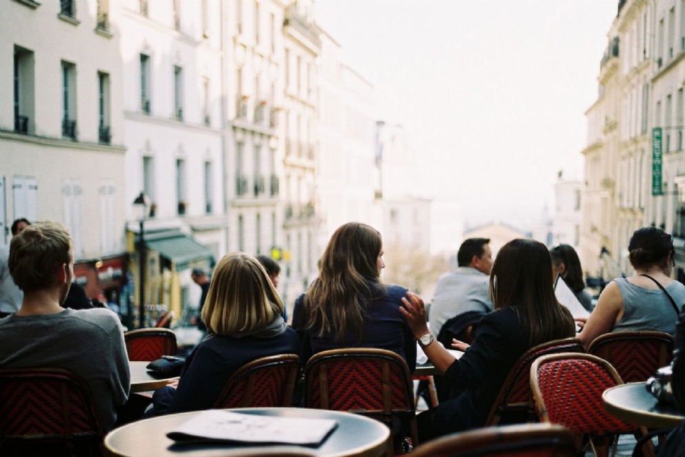 Persone sedute ai tavolini di un bar